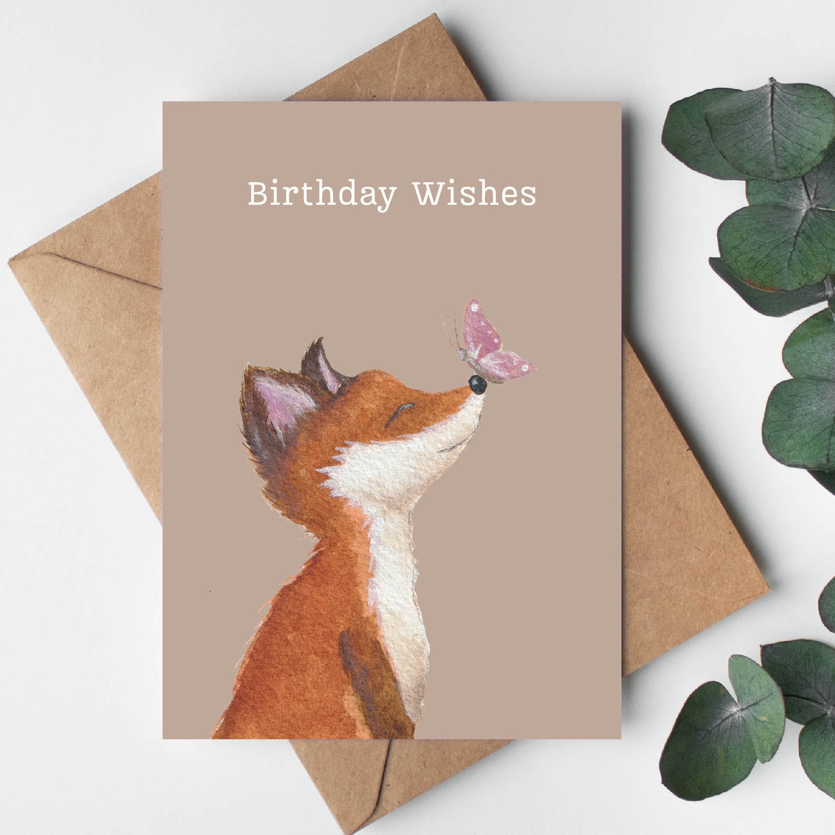 Birthday card with fox illustration and 'Birthday Wishes' text, surrounded by eucalyptus leaves on a light background.