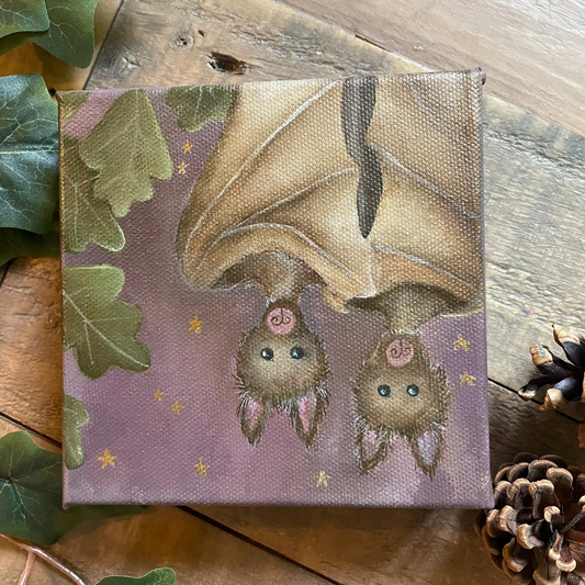Canvas print of a bat and two baby bats on a purple background with green leaves and pinecones around.