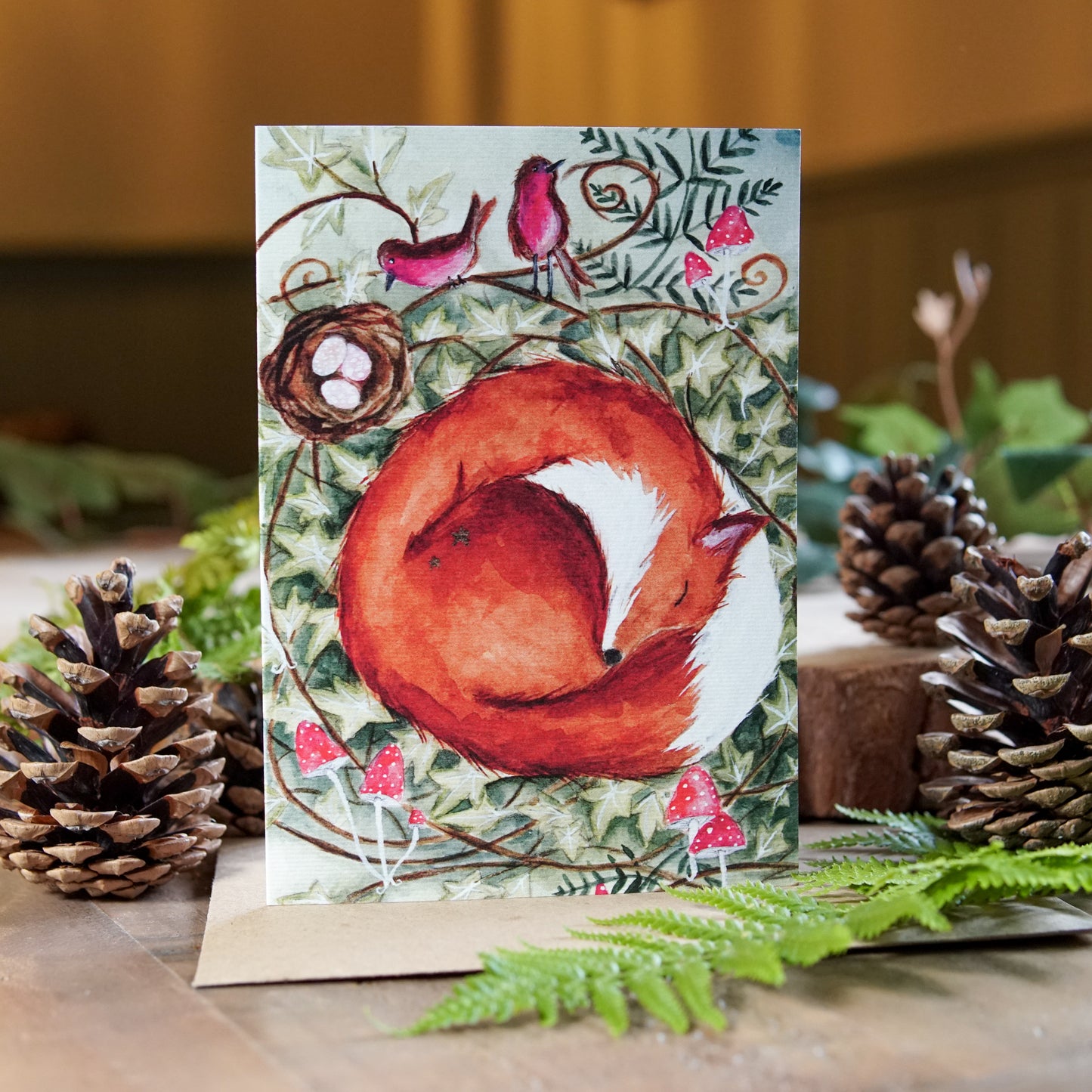 Sleepy fox curled up in a woodland nest among toadstools on a greeting card