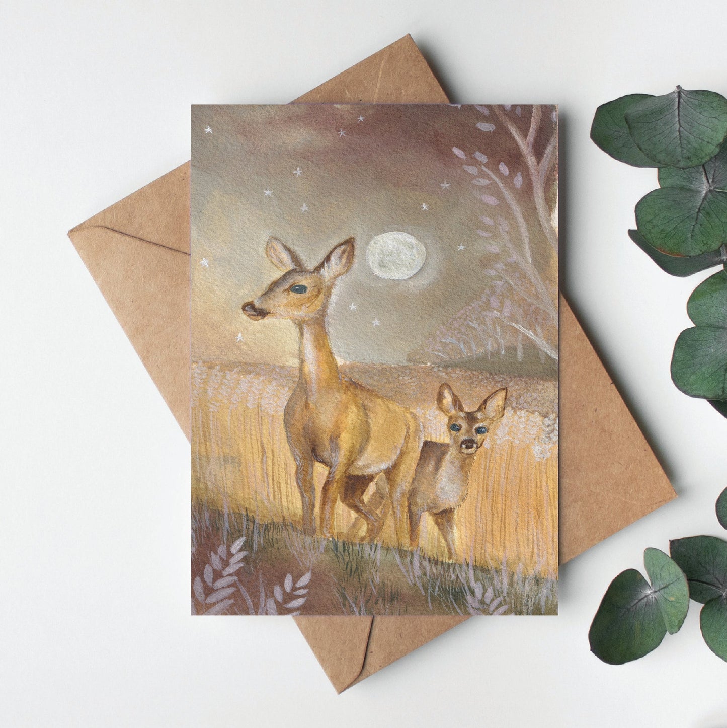 Greeting card with deer illustration on a white background with eucalyptus leaves.