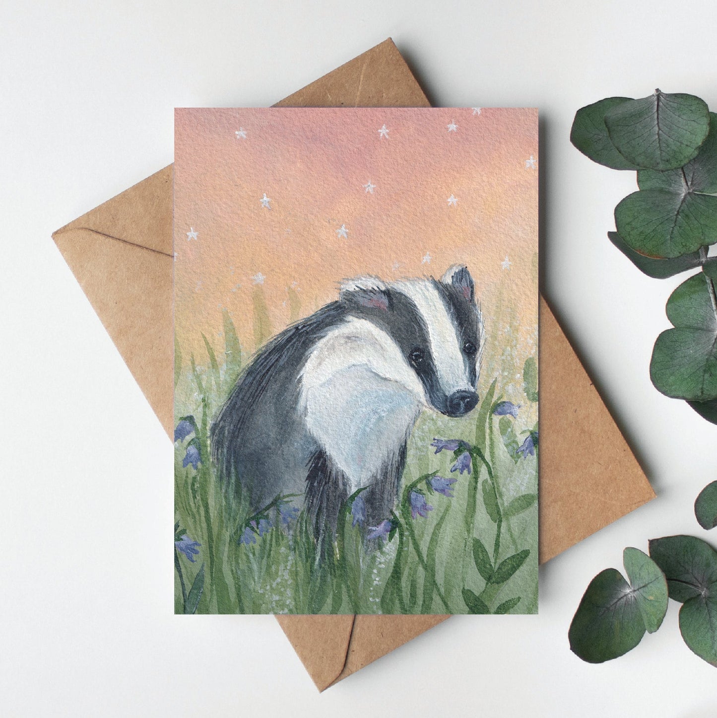 Greeting card with a badger illustration on a white background with eucalyptus leaves.
