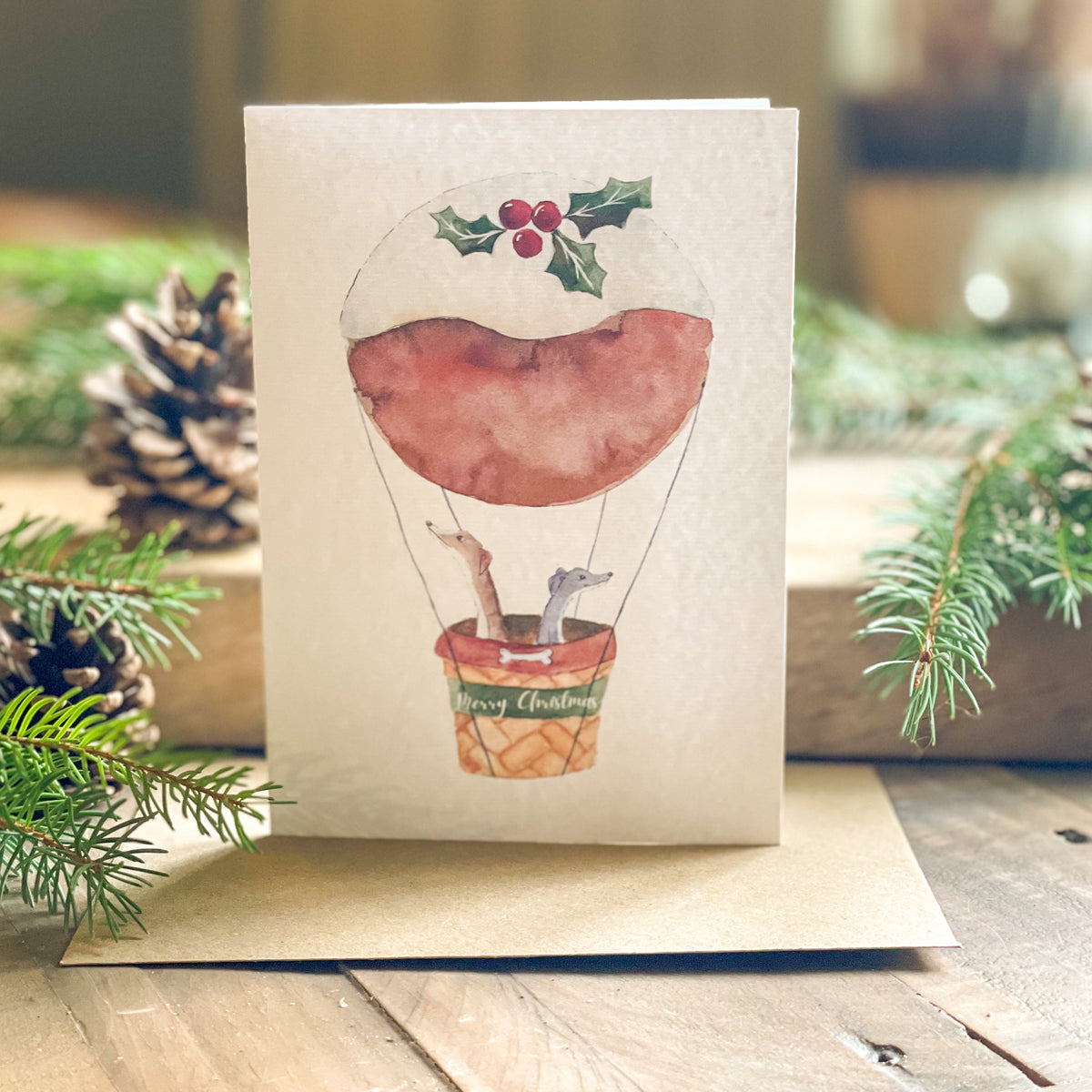 Whippet Christmas Pudding card by Zoë Rose Art featuring two whippets flying in a festive Christmas pudding hot-air balloon